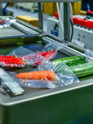 Fresh vegetables packed in a clear plastic wrap production line in factory, industrial food production Fresh vegetables packed in a clear plastic wrap production line in factory, industrial food production